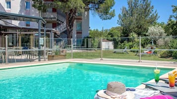 Una piscina al aire libre, sombrillas, sillones reclinables de piscina