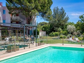 Una piscina al aire libre, sombrillas, sillones reclinables de piscina