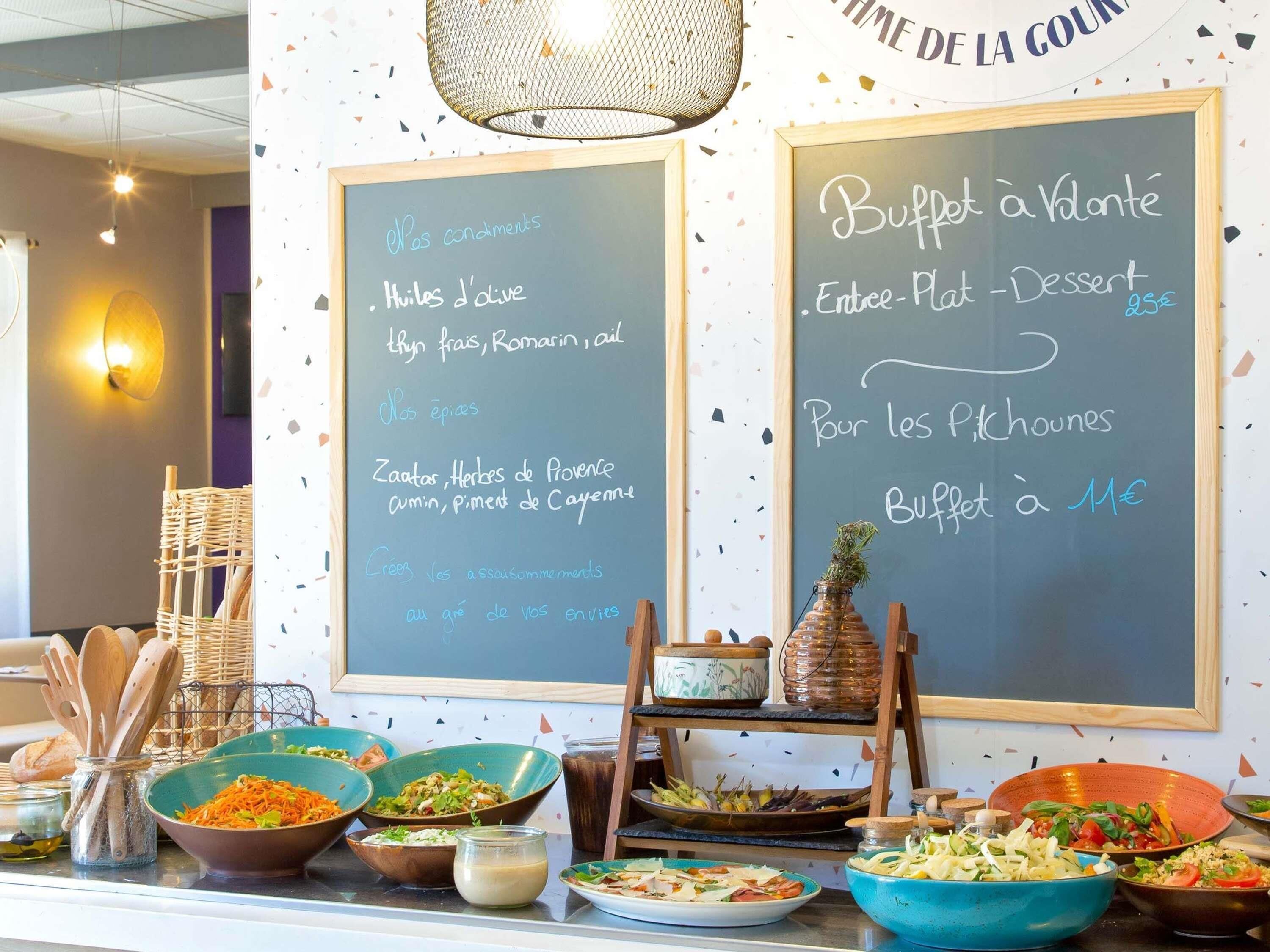 A buffet area with chalkboard menus listing food items and prices.