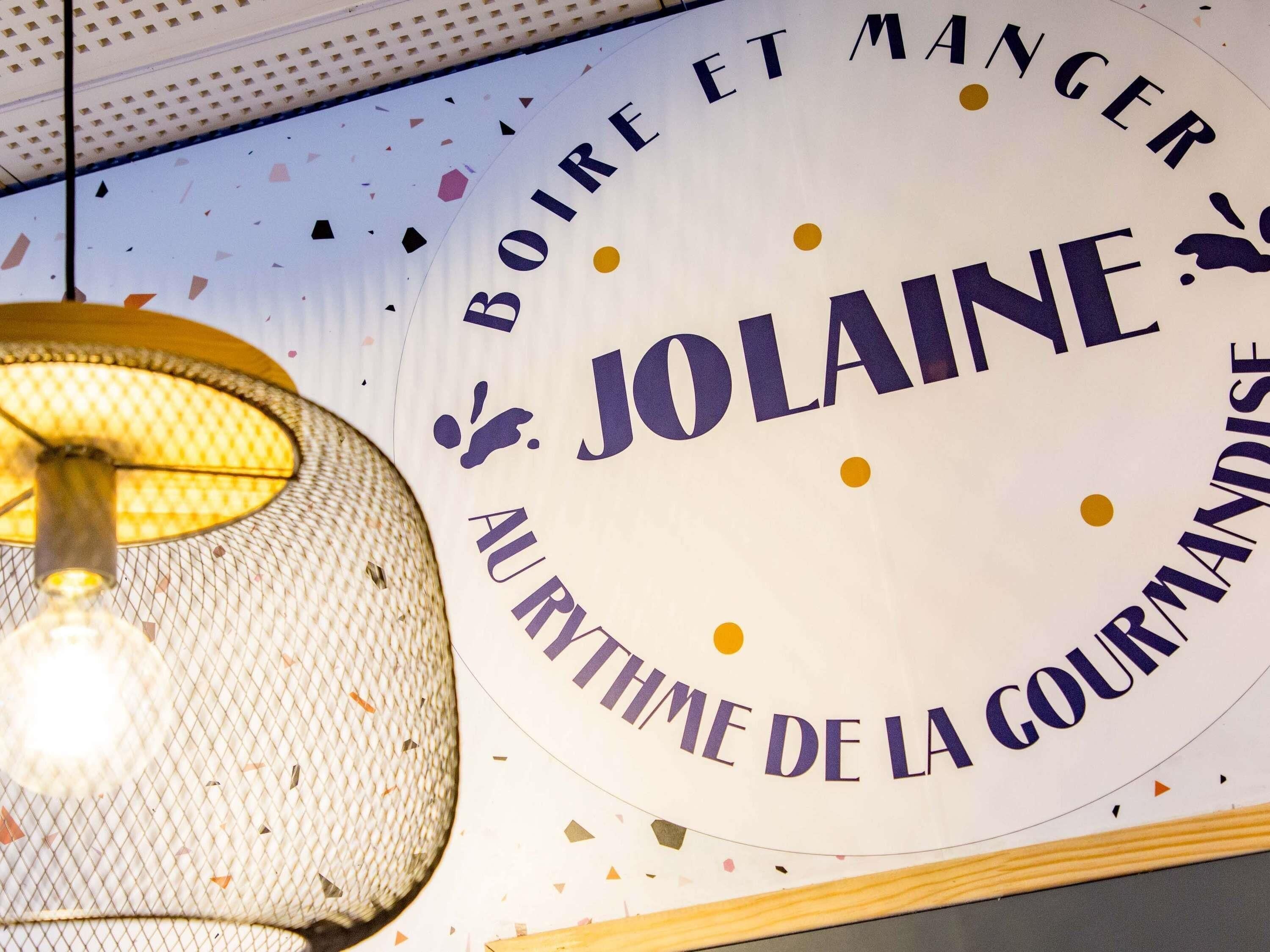 Une enseigne portant les inscriptions « BOIRE ET MANGER » et « JOLAINE », indiquant un établissement où l’on peut manger et boire.