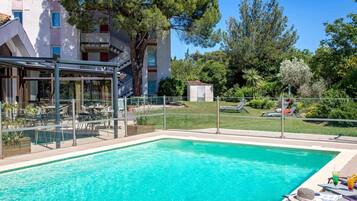 Una piscina al aire libre, sombrillas, sillones reclinables de piscina