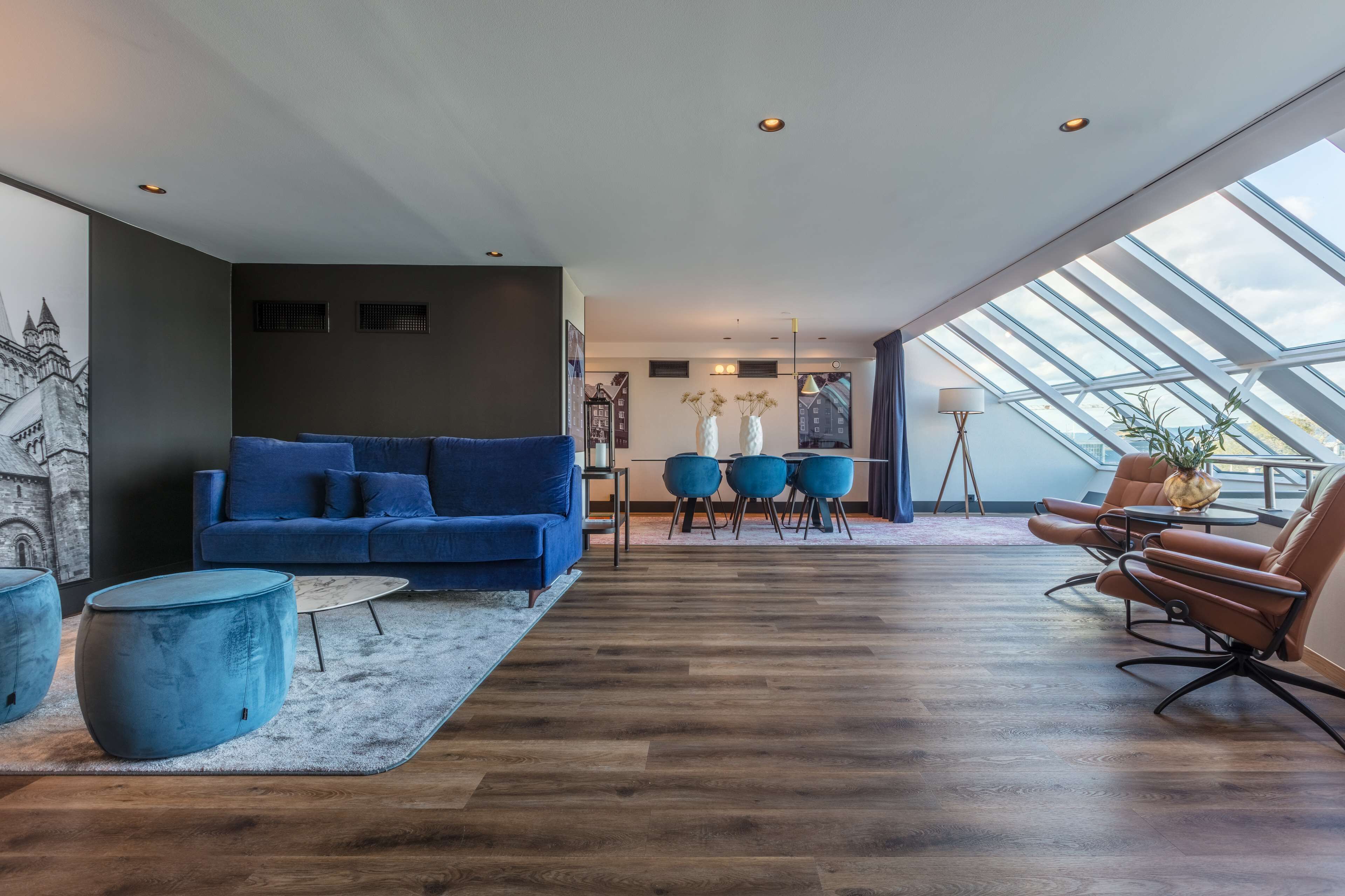 Una sala de estar moderna con un sofá azul, una mesita redonda y un comedor con una mesa pequeña y sillas.