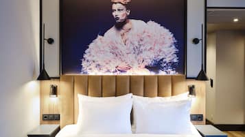 A hotel room with a large bed, two bedside tables, a wall-mounted TV, and a modern headboard.