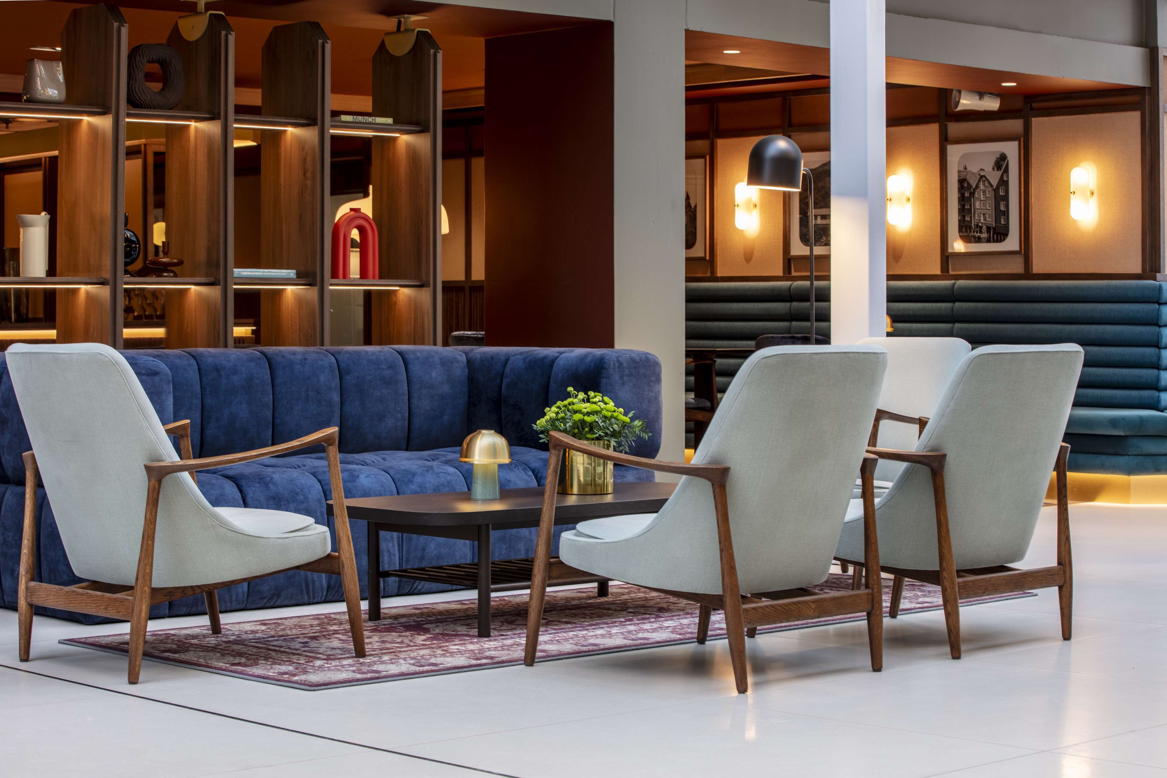 A modern lounge area with a blue sofa, two armchairs, and a round table.