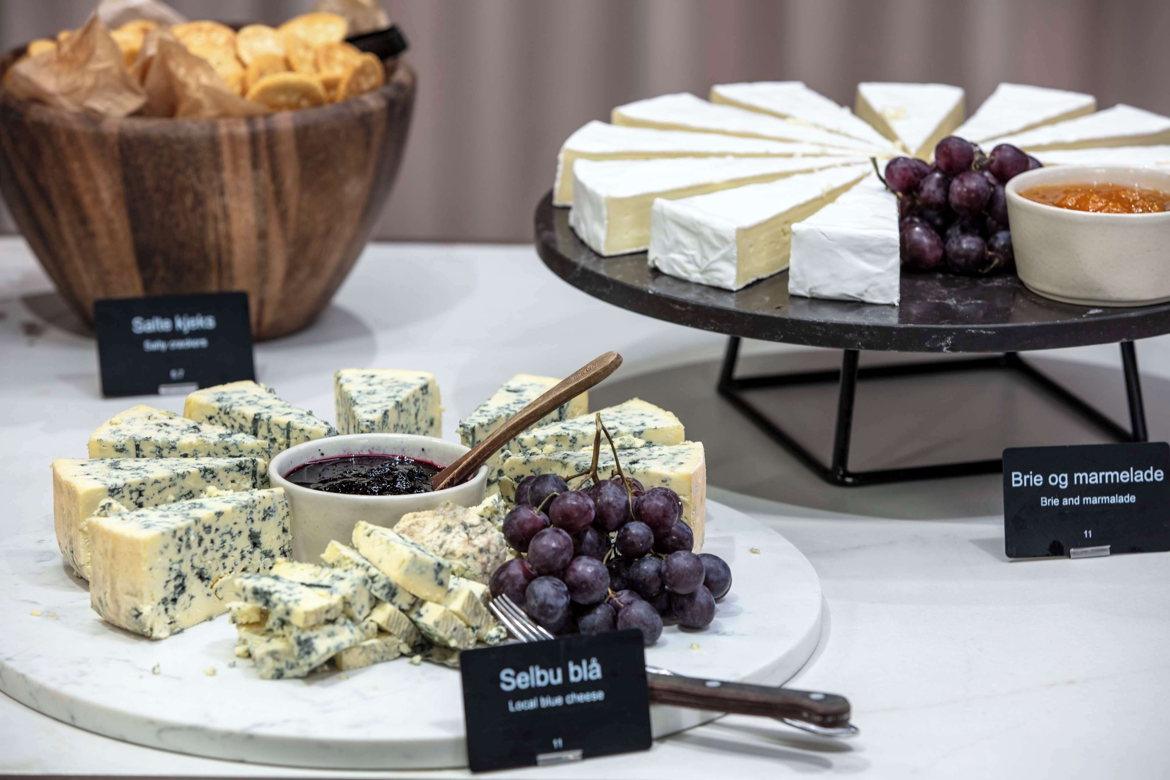 A cheese board with various types of cheese, grapes, and a bowl of crackers.