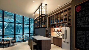 A modern kitchen with a large island, wooden cabinets, and a view through the glass walls. - Charlotte Marriott City Center (Charlotte)