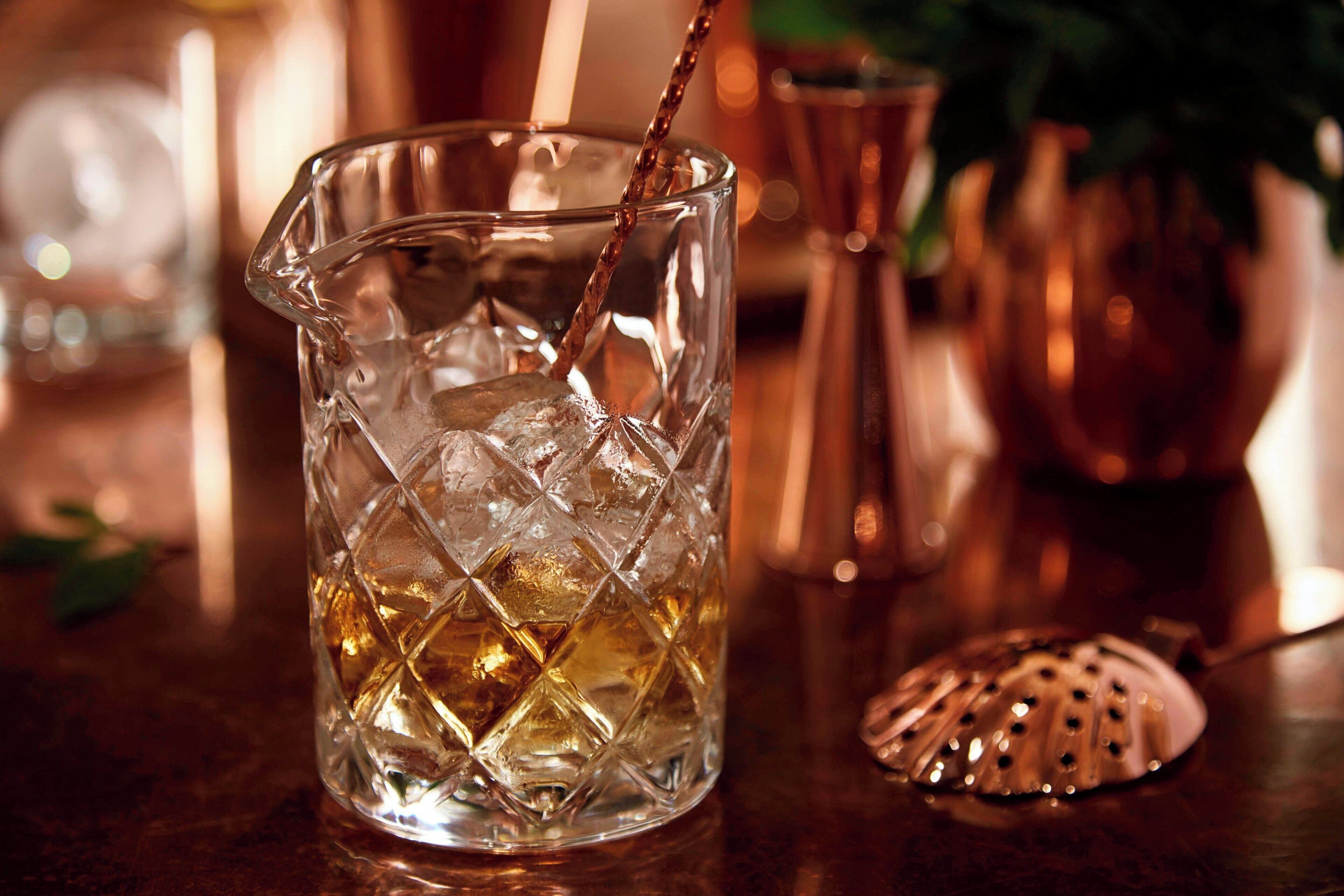 Une carafe en verre transparent contenant de la glace et dans laquelle on verse un liquide.