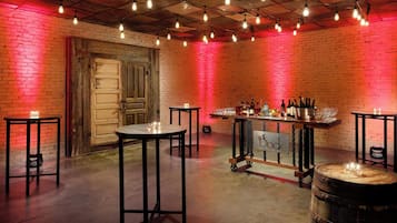 Zona de bar con mesas, taburetes y barra con botellas y vasos.