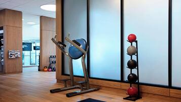 A gym with exercise equipment, a rack of weights, and a yoga mat.