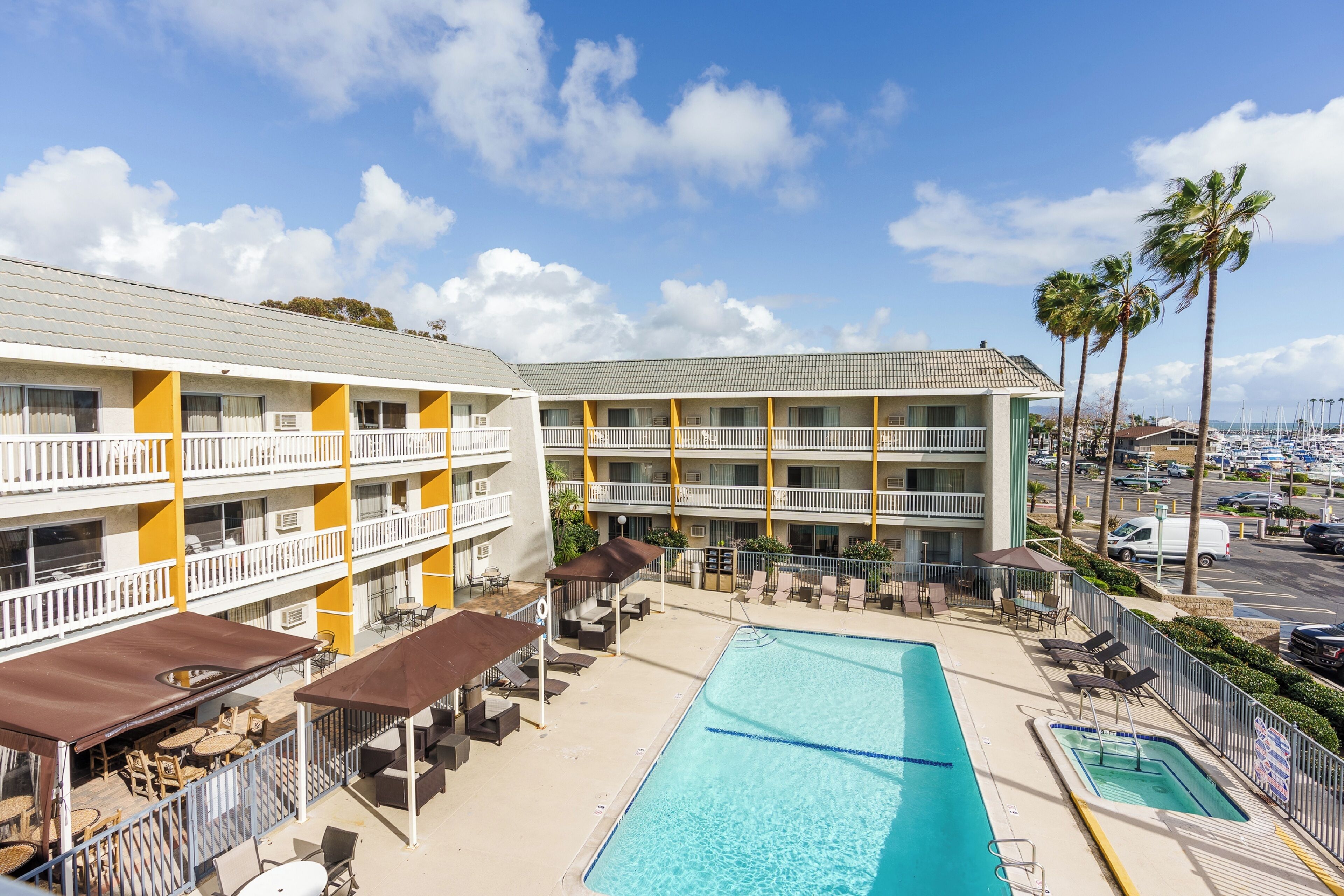 A hotel with a pool, outdoor seating, and a parking lot.