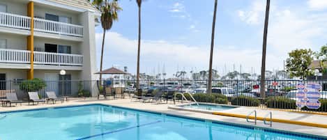A swimming pool with lounge chairs and a building with balconies.