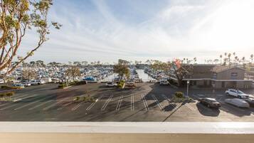A marina with boats docked, a parking lot with cars, and a building with a sign.