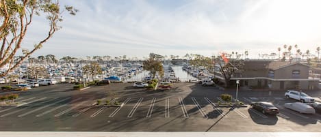 A marina with boats docked, a parking lot with cars, and a building with a sign.