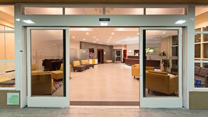 A spacious lobby with a reception desk, seating area, and a clear view into the interior. - Pacific Stay Hotel (West Covina)
