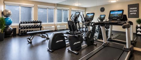 A gym with treadmills, elliptical machines, and free weights.