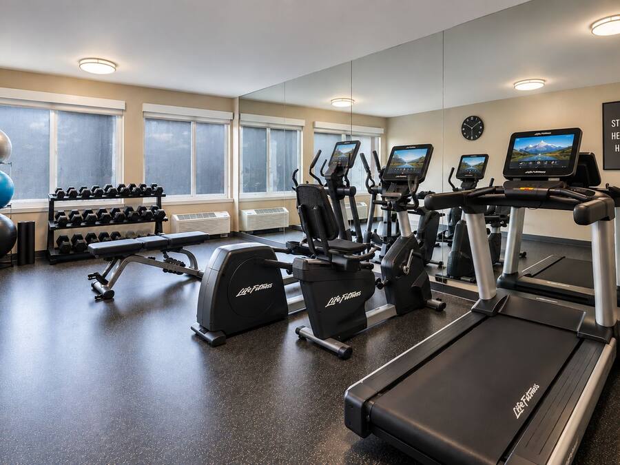 Un gimnasio con cintas de correr, elípticas y pesas sueltas.