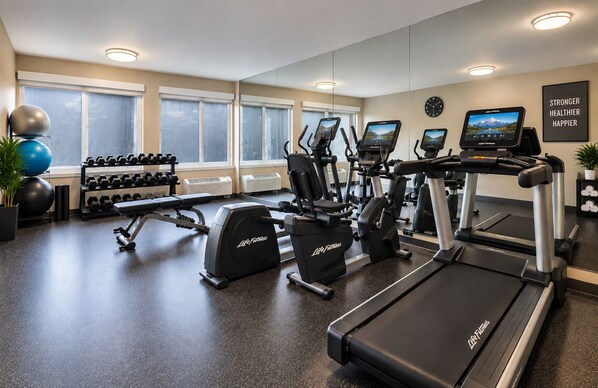A gym with treadmills, elliptical machines, and free weights.