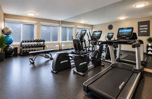 Un gimnasio con cintas de correr, elípticas y pesas sueltas.