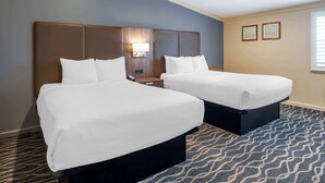 A hotel room with two beds, a nightstand, a lamp, and a patterned carpet. - Best Western Plus Hill House (Bakersfield)