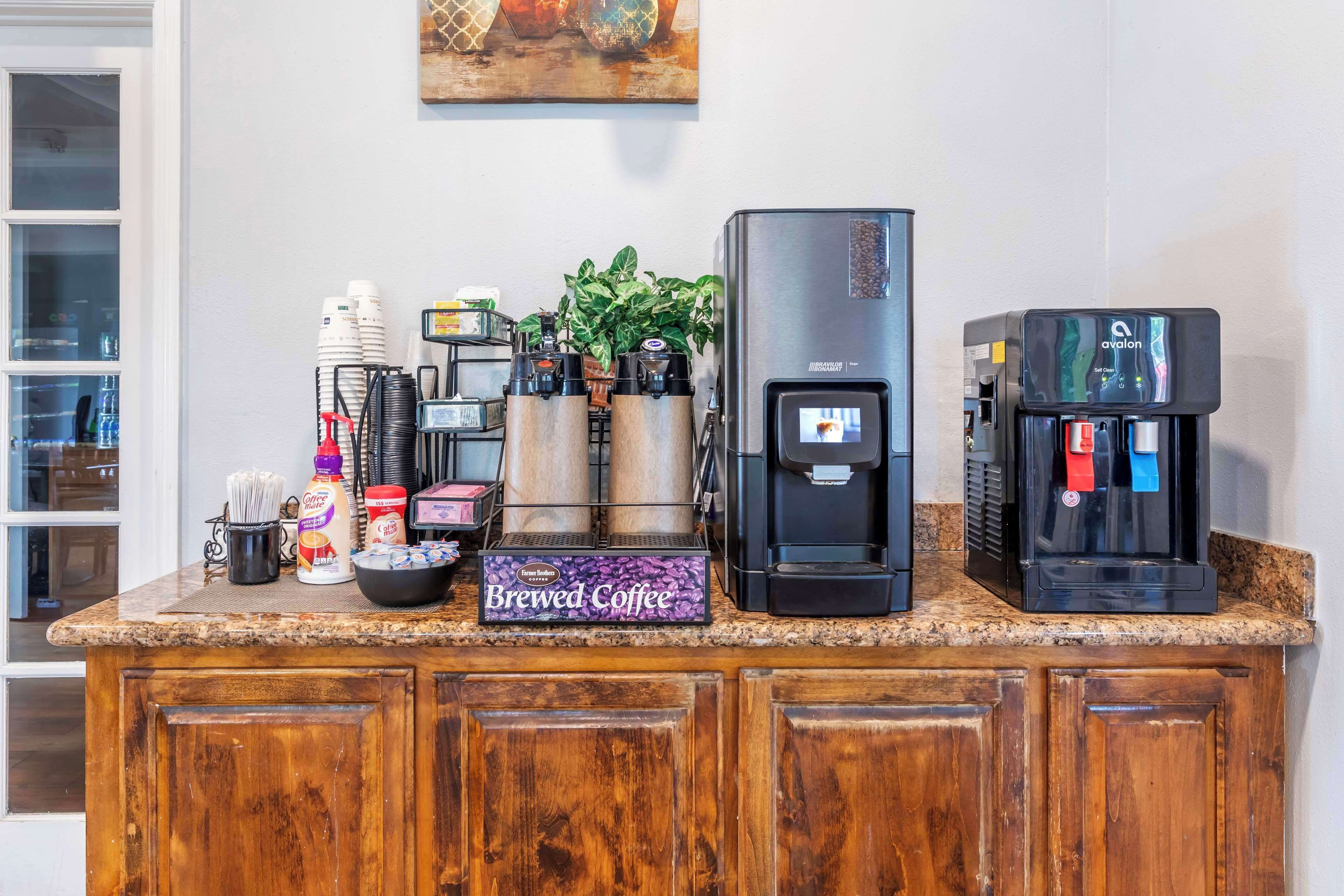 Una encimera de cocina con equipo para preparar café, incluyendo una cafetera, un dispensador de café y una caja de café ya preparado.