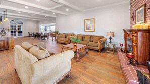 A spacious living room with a fireplace, sofas, and a dining area. - Best Western Plus Hill House (Bakersfield)