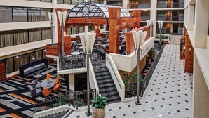 A multi-level hotel atrium with a central staircase, seating areas, and a glass-enclosed structure.