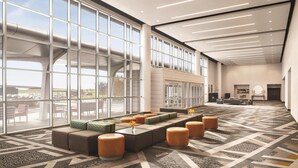 A spacious lobby with large windows, a seating area with sofas and ottomans, and a reception desk.