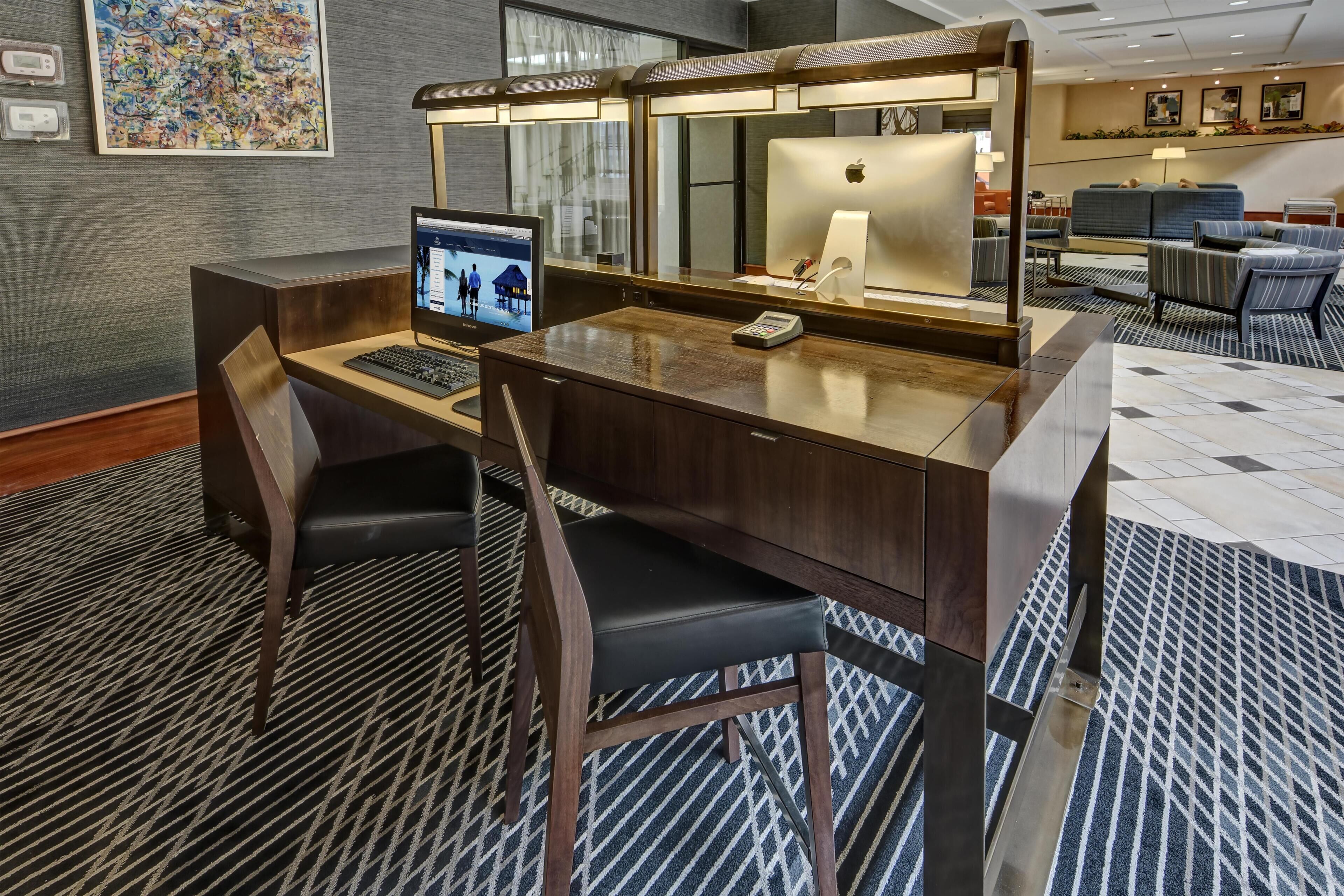 Eine Hotelhalle mit Empfangsschalter, Computer und Sitzgelegenheiten.