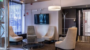 A modern lobby with a large TV, comfortable seating, and a reception area. - Scandic Kaisaniemi (Helsinki)