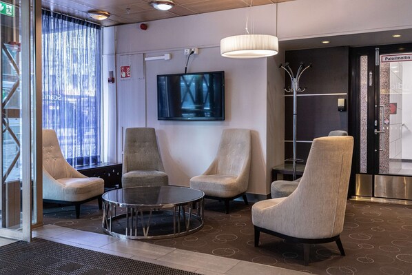 A modern lobby with a large TV, comfortable seating, and a reception area. - Scandic Kaisaniemi (Helsinki)