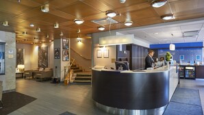 A modern hotel lobby with a reception desk, seating area, and a staircase. - Scandic Kaisaniemi (Helsinki)