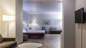 A modern hotel room with a bed, a sofa, a small table, and a TV. - Scandic Kaisaniemi (Helsinki)