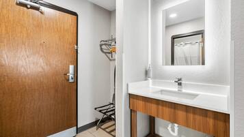 Un baño moderno con una puerta de madera, un lavabo blanco y un espejo.