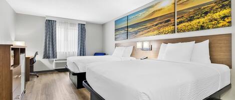 A hotel room with two beds, a desk, a chair, a wardrobe, and a large landscape painting on the wall.