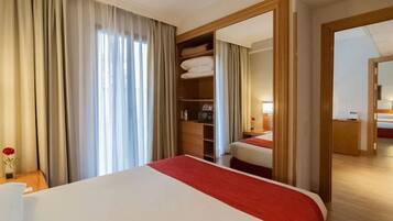 A hotel room with a large bed, a wardrobe, a mirror, and a bedside table with a vase of flowers.