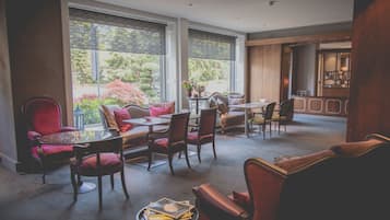 Une pièce spacieuse dotée de grandes fenêtres, d’un coin repas et d’un espace salon avec plusieurs chaises et tables.