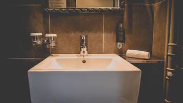 Ein Badezimmer mit einem weißen Waschbecken, einem Spiegel und einem Handtuchhalter.