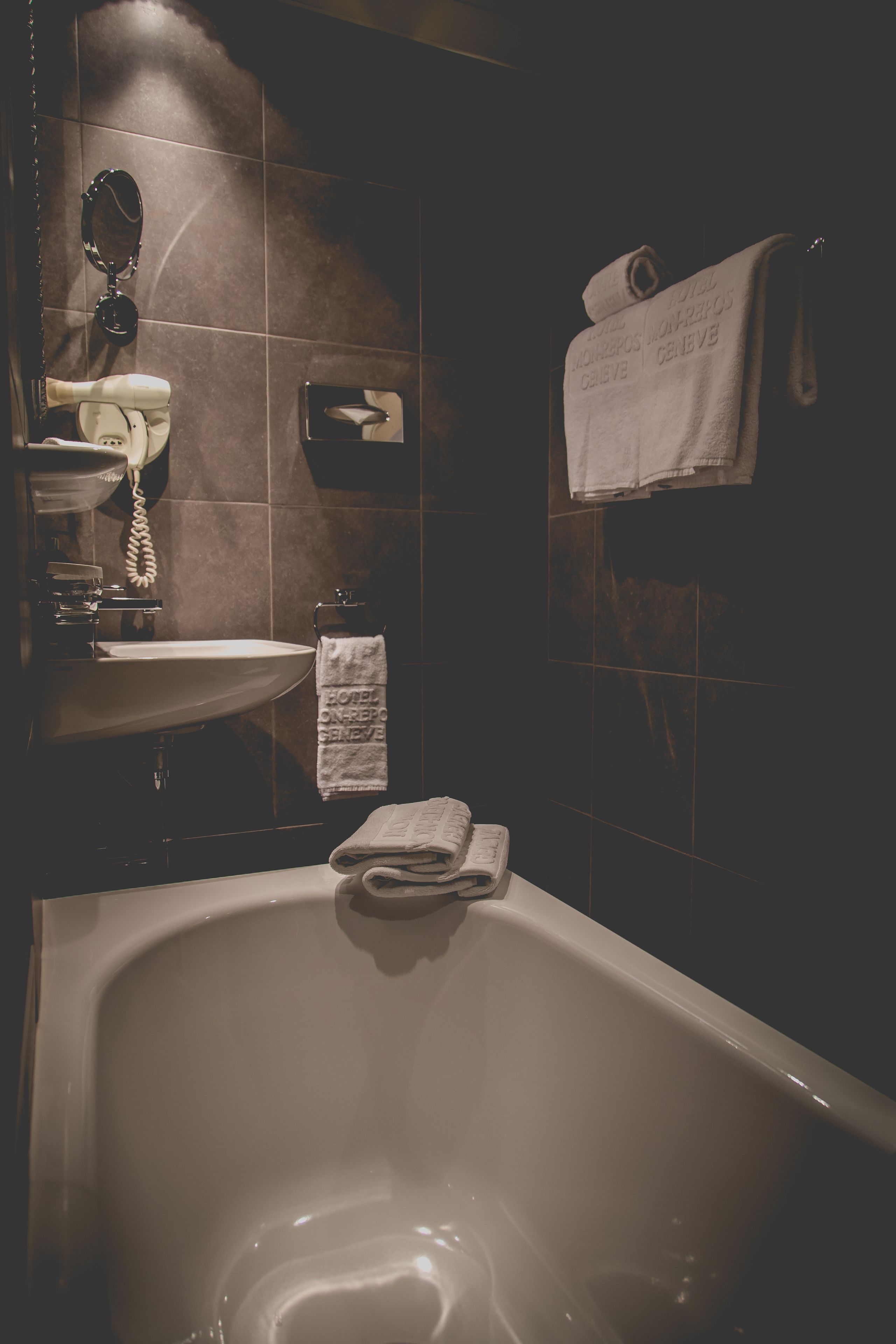 A bathroom with a bathtub, a sink, a mirror, and a towel rack.