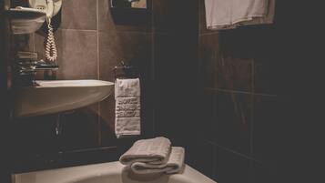 A bathroom with a bathtub, a sink, a mirror, and a towel rack.
