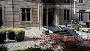 Un edificio con una entrada moderna, una escalera cubierta y plantas en macetas al frente.