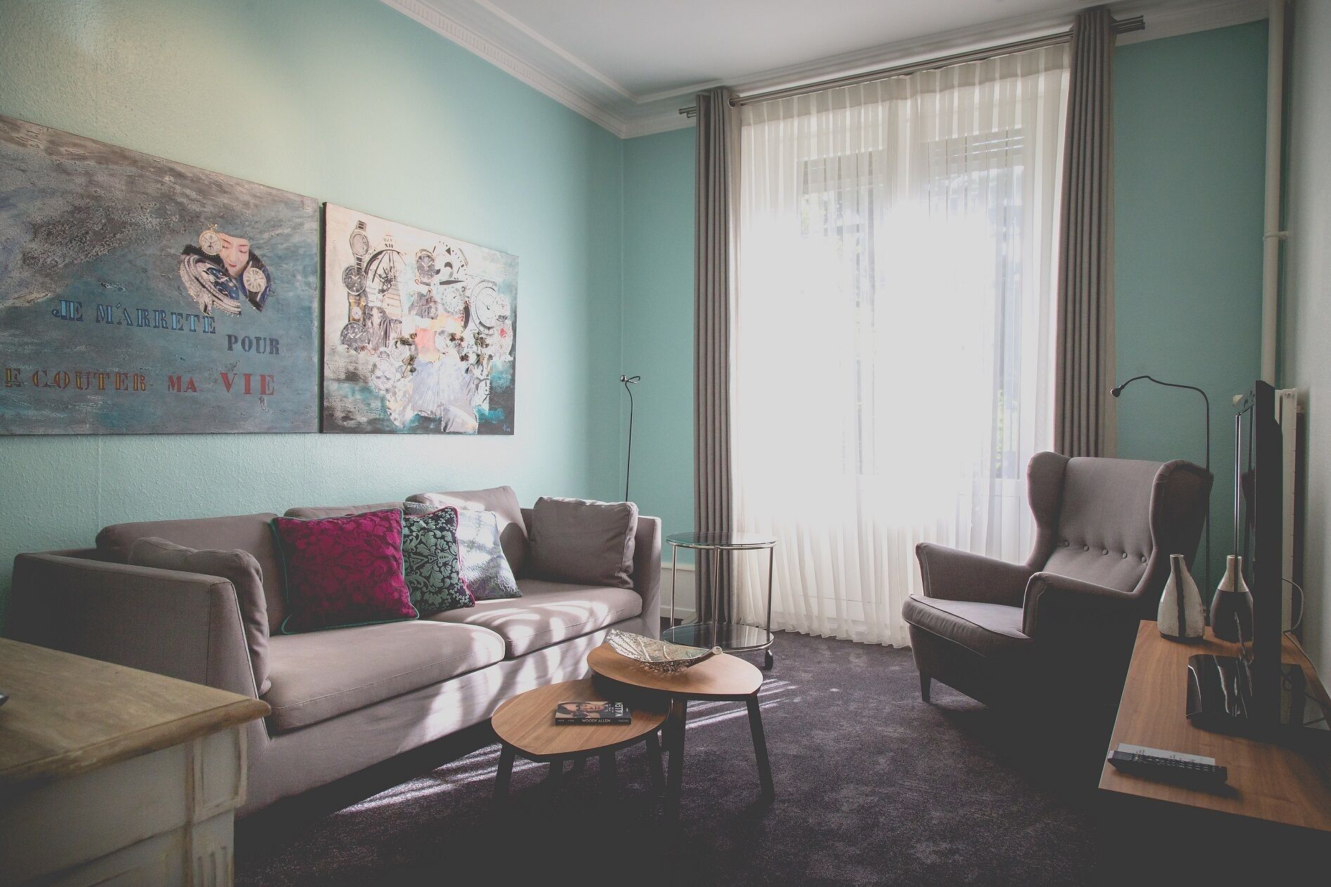 Una sala de estar con un sofá, sillones, una mesa de centro y obras de arte en la pared.