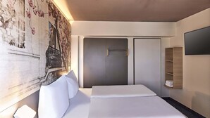 A modern hotel room with a large bed, a wardrobe, and a wall-mounted TV. - B&B Hotel Bonn-City (Bonn)