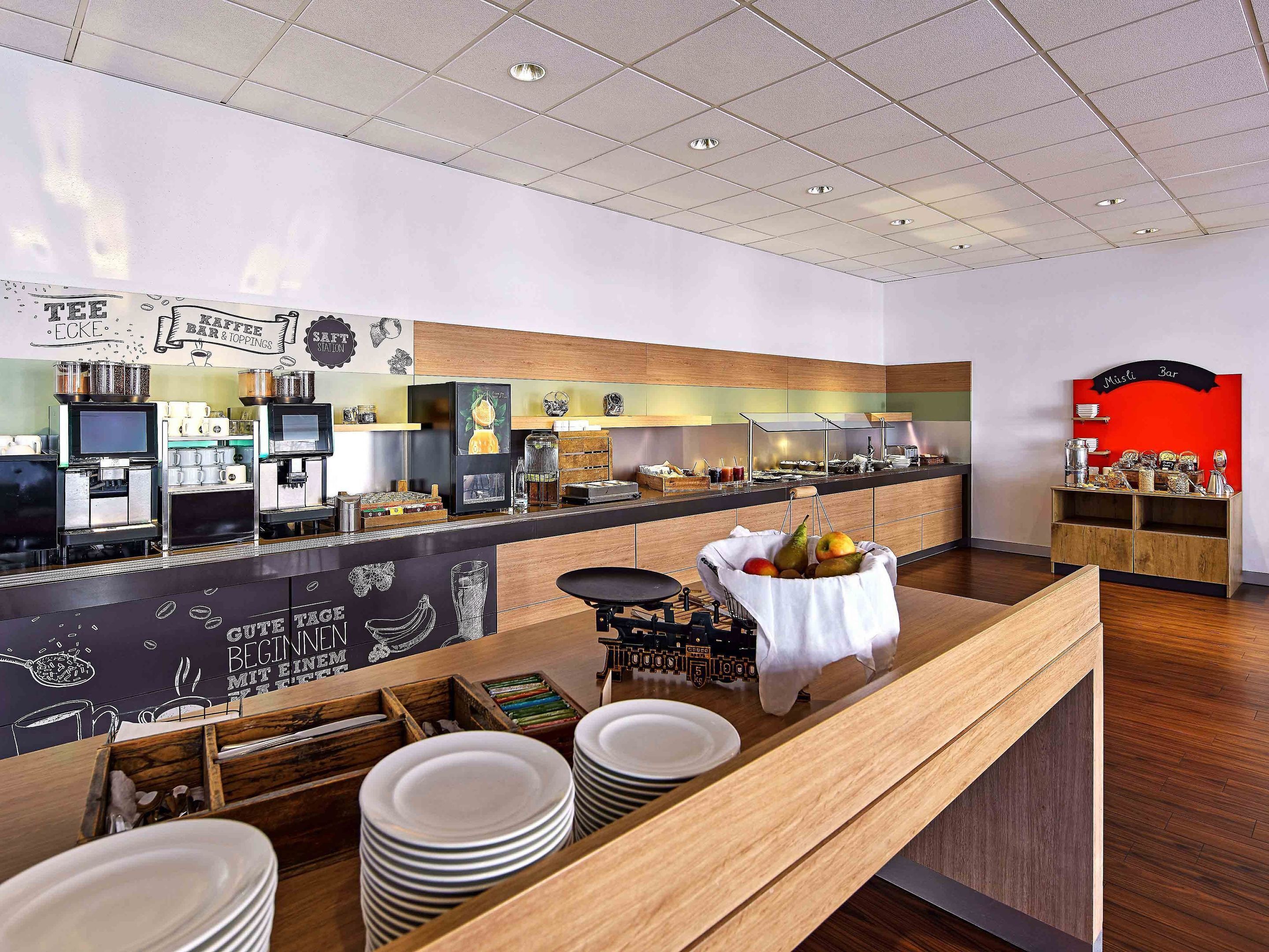 A modern cafe with a counter, coffee machines, and a variety of food items displayed.