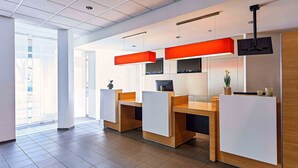 A modern office space with cubicles, a large window, and a ceiling with recessed lighting. - B&B Hotel Bonn-City (Bonn)