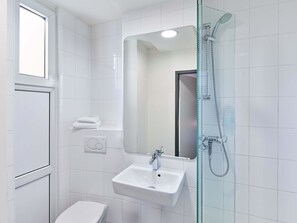 A modern bathroom with a glass shower enclosure, a white sink, and a toilet. - B&B Hotel Bonn-City (Bonn)