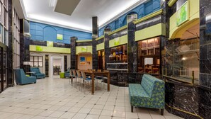 A spacious lobby with a tiled floor, a central seating area with a table and chairs, and a sofa.