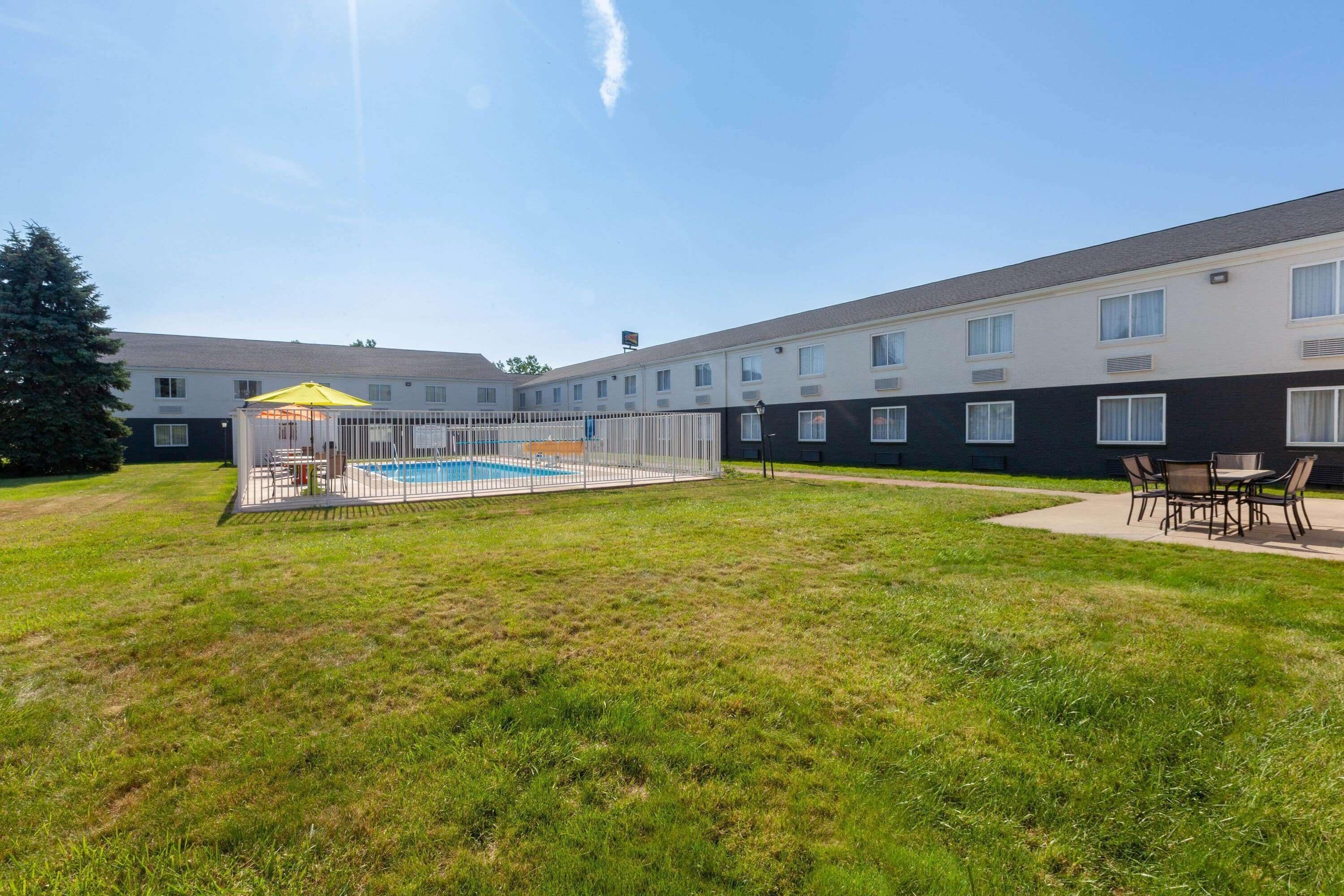 A courtyard with a swimming pool, outdoor seating, and a building with multiple windows.