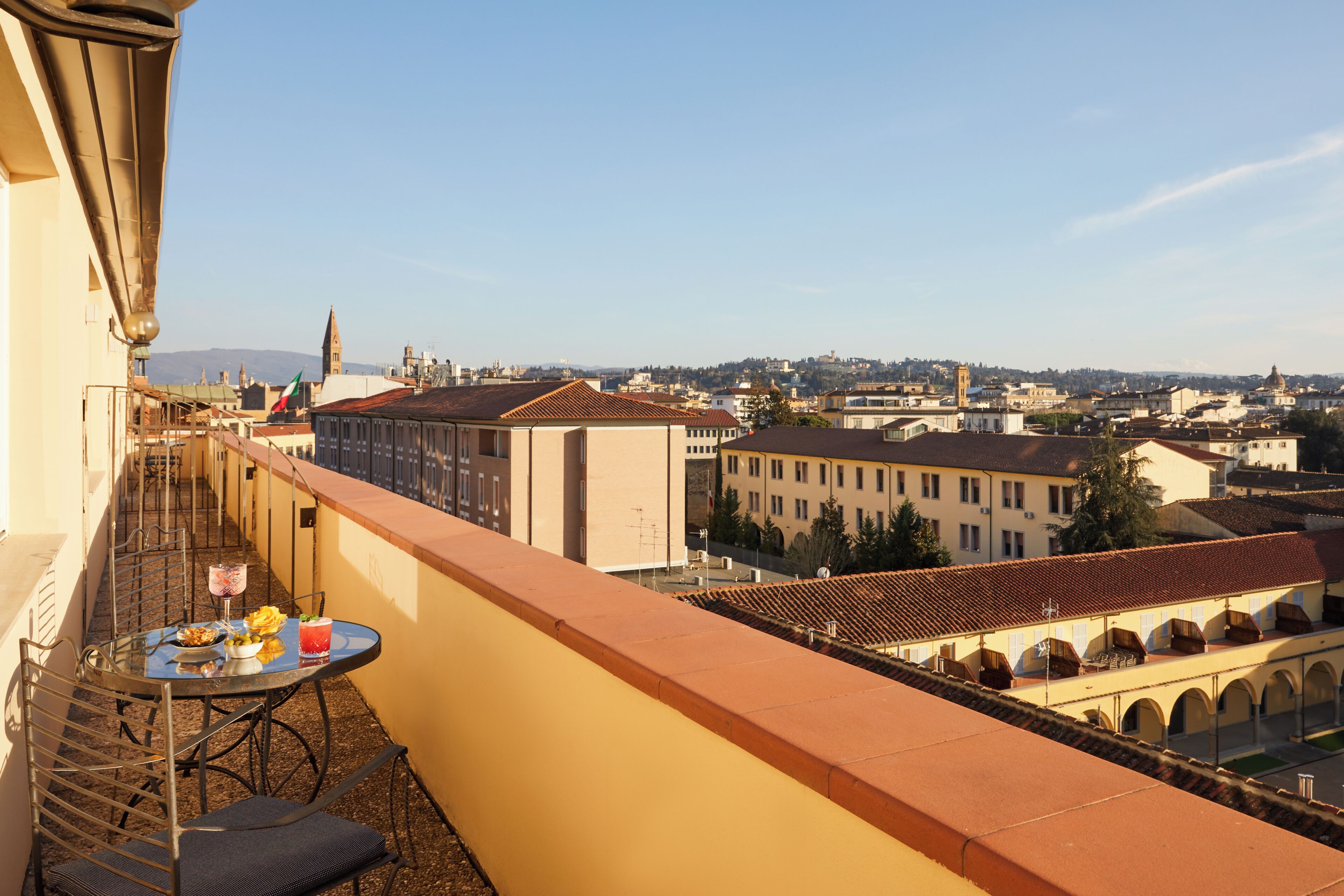 A balcony with a table set for two, overlooking a cityscape with historic buildings.