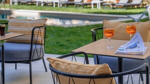 Un espace aménagé au bord de la piscine, avec des chaises longues et une table où sont servis des boissons et où l’on peut consulter le menu.