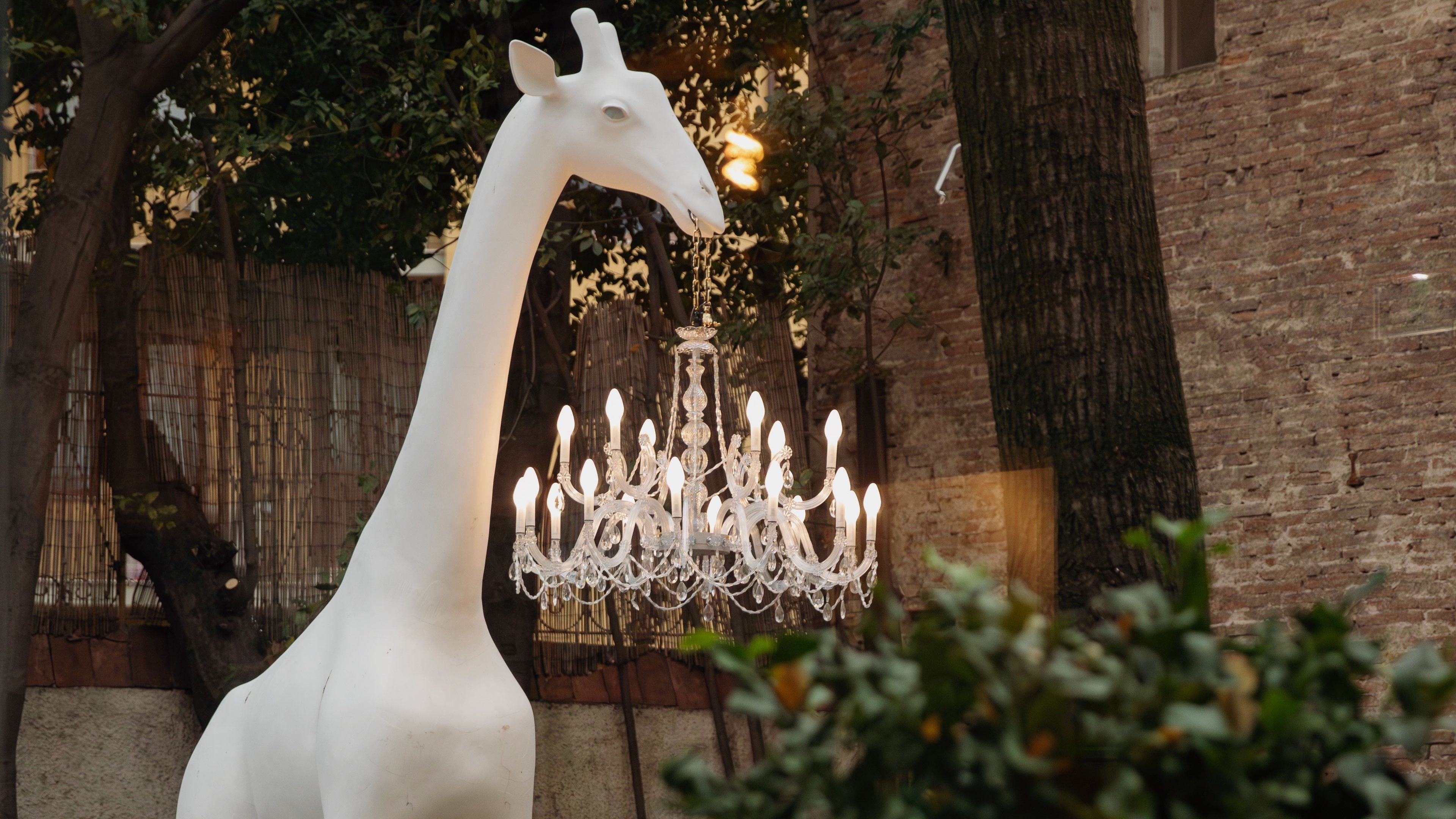 A giraffe sculpture next to a chandelier.